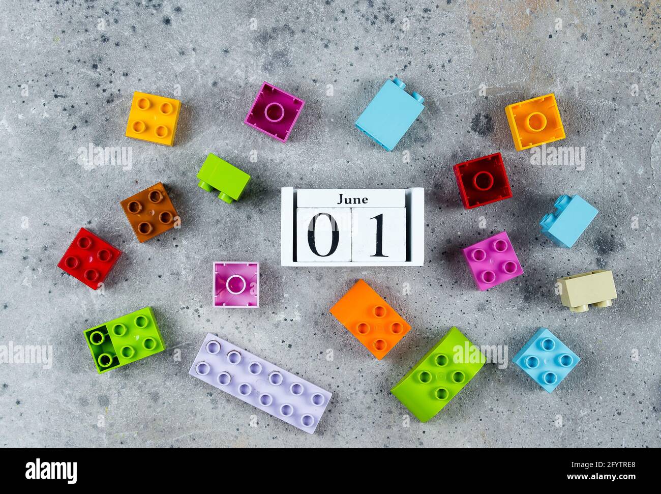 Buon giorno per i bambini. Cubi di legno data calendario 1 giugno e cubi colorati di plastica su sfondo grigio. Modello di posa piatta Creative Top View Foto Stock