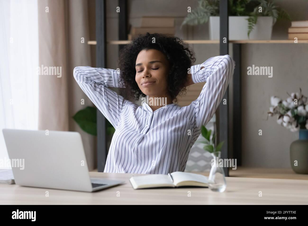 Calma biraciale donna rilassarsi alla scrivania in ufficio casa Foto Stock