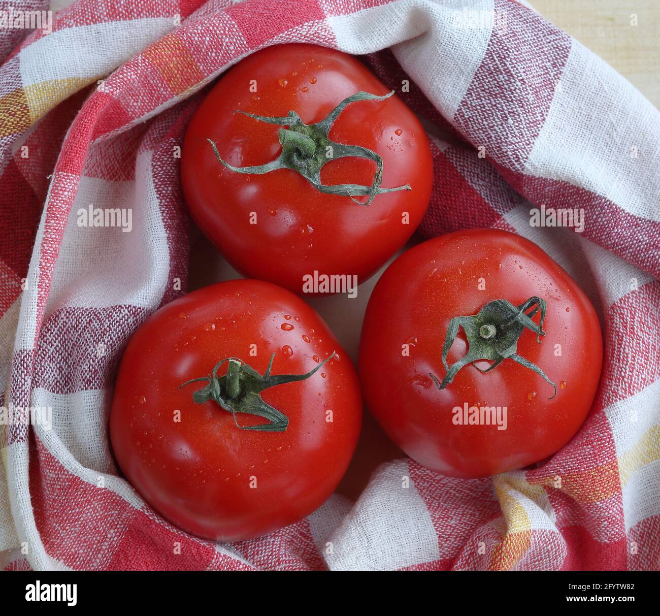 Tre pomodori biologici ecologici freschi con biancheria da cucina stoffa vista dall'alto. Foto Stock