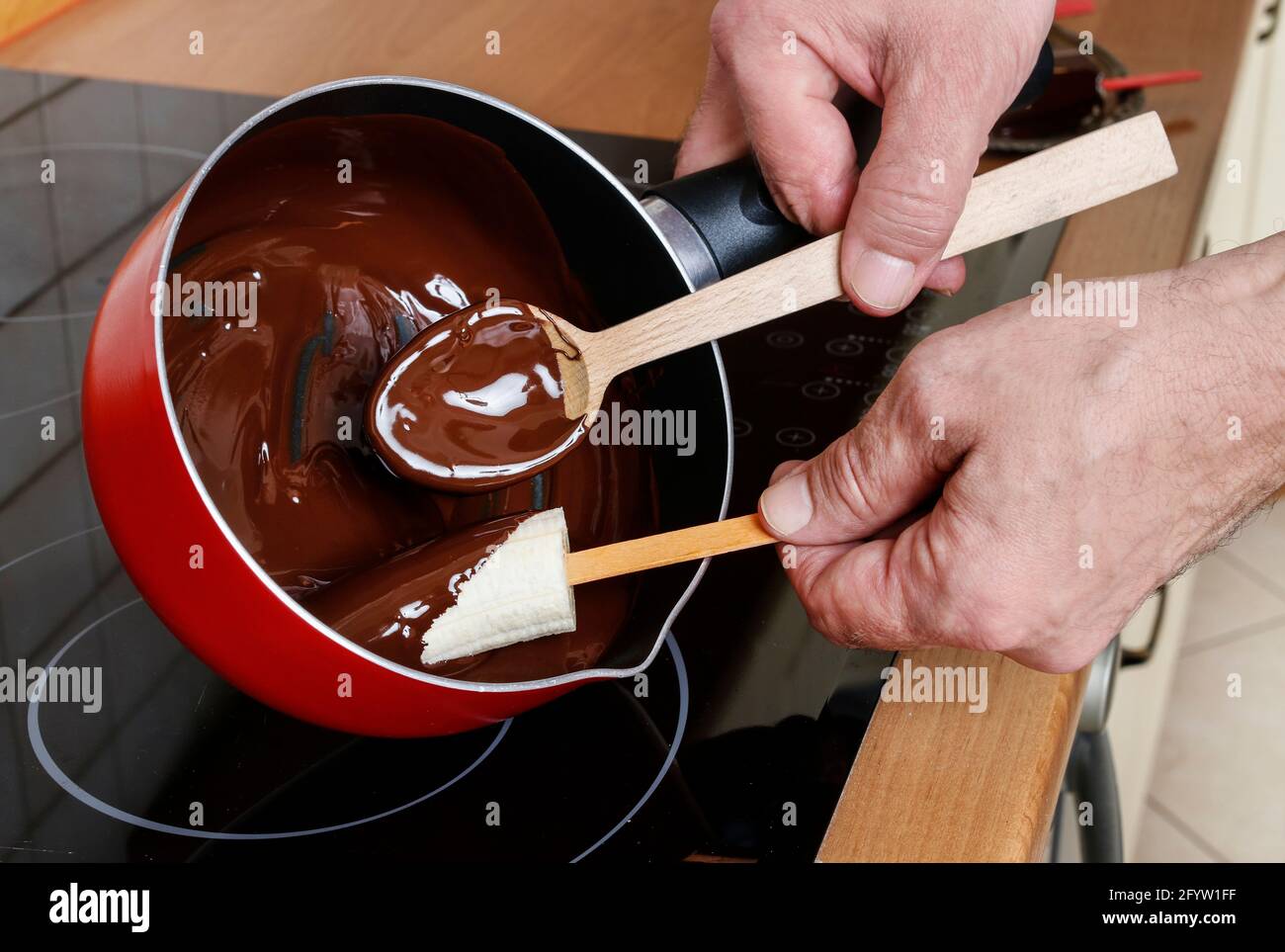 Uomo che prepara le banane immerse nel cioccolato. Dessert sano Foto Stock