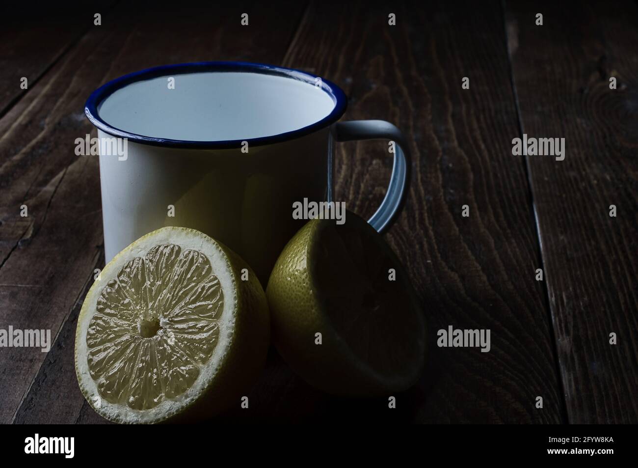 Un primo piano di un limone tagliato e di un bianco tazza su un tavolo di legno Foto Stock