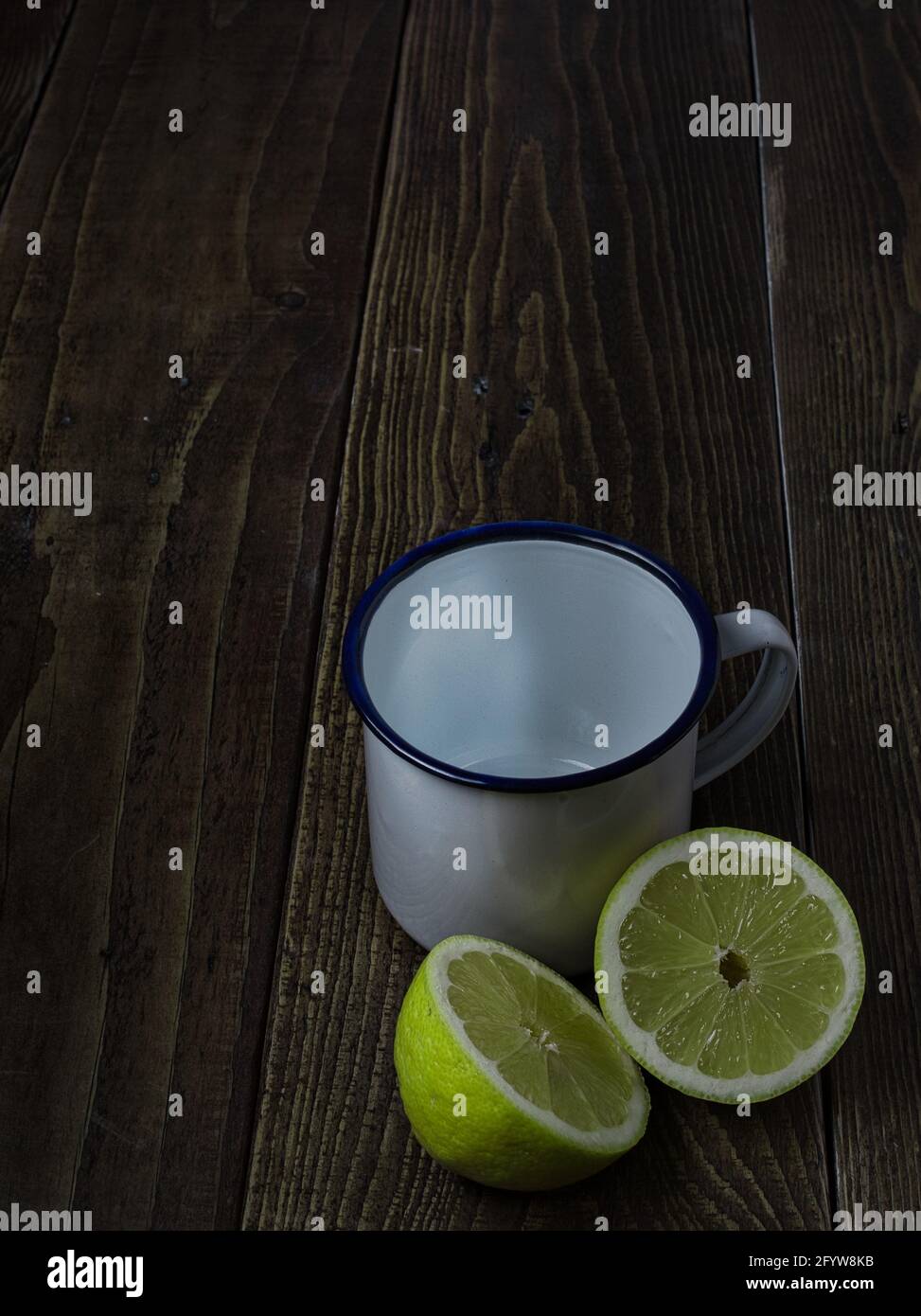 Un colpo verticale di un limone tagliato e di un bianco tazza su un tavolo di legno Foto Stock