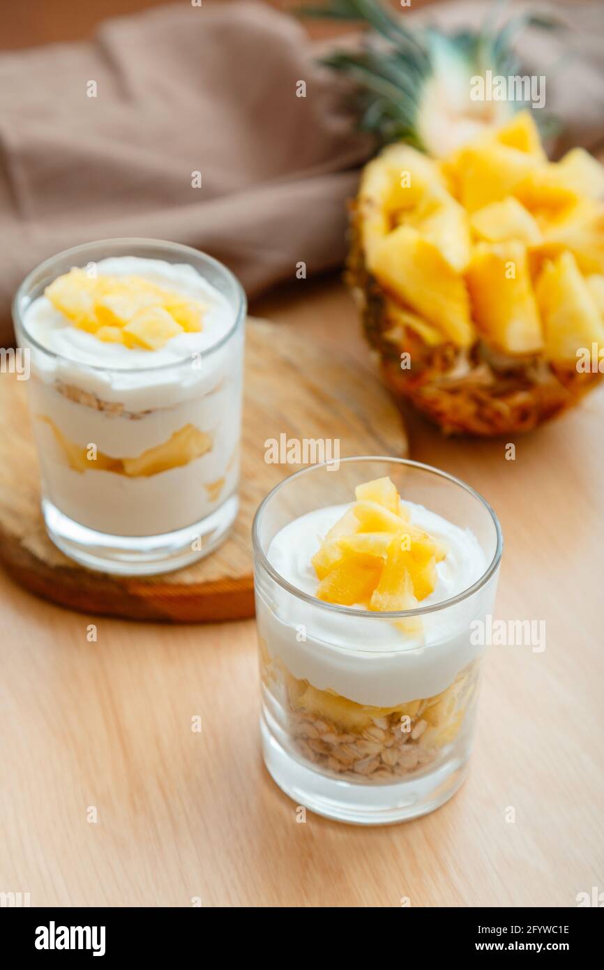 Due gustosi dessert all'ananas. Prima colazione dessert con granola di avena, yogurt greco e ananas a strati in vetro con ingredienti tritati freschi succosi Foto Stock