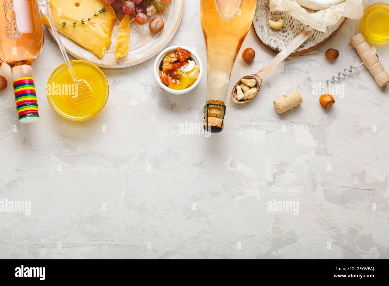 Vino rosa e composizione di formaggio su fondo rustico in cemento grigio chiaro con spazio copia. Bottiglia di vino rosato formaggio noci uve rosa. Camembert Foto Stock