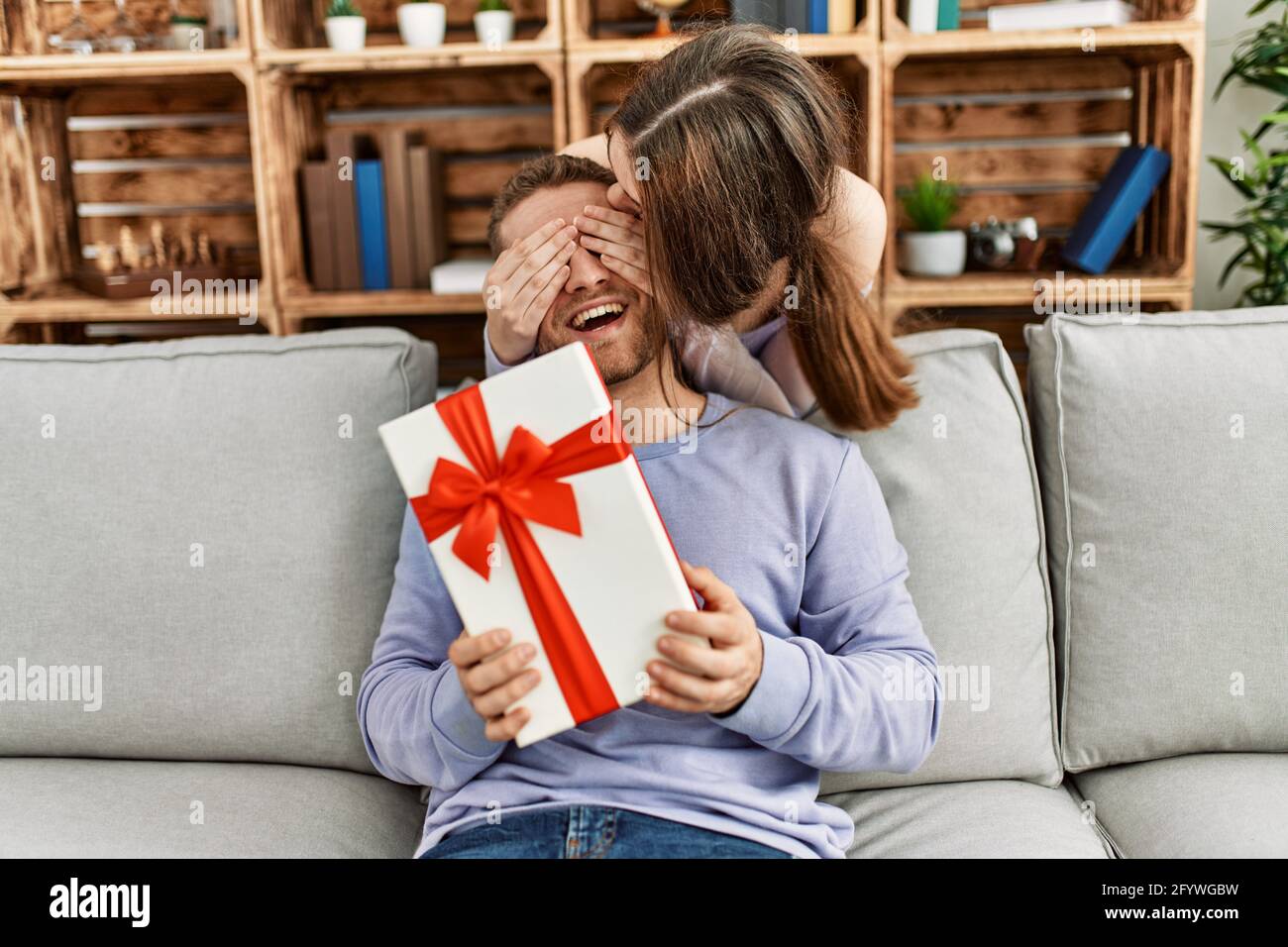 Giovane donna sorprende il suo ragazzo con regalo di compleanno a casa Foto  stock - Alamy