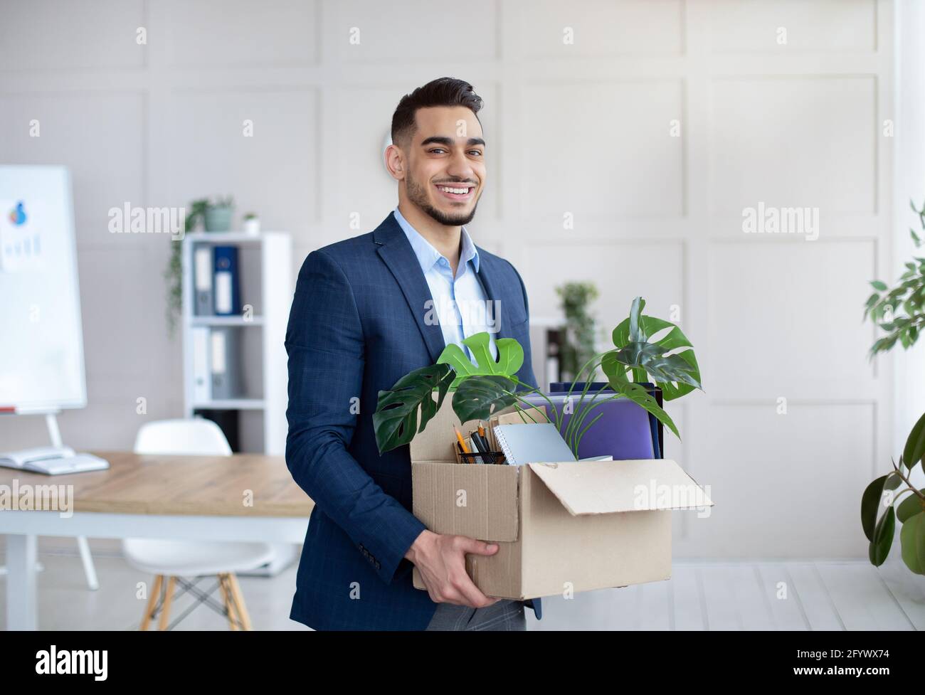 Primo giorno in ufficio. Ritratto di uomo d'affari arabo fiducioso con gli effetti personali che si spostano in un nuovo ufficio Foto Stock