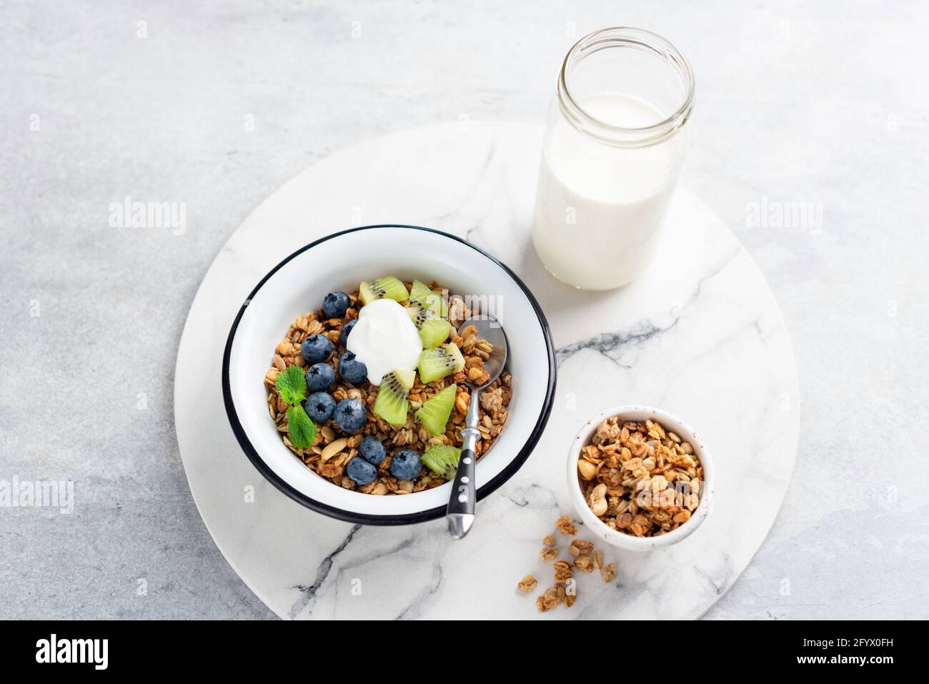 Granola fatta in casa con yogurt greco e frutta in una ciotola su tavola di marmo. Cibo sano per la colazione, cereali d'avena Foto Stock