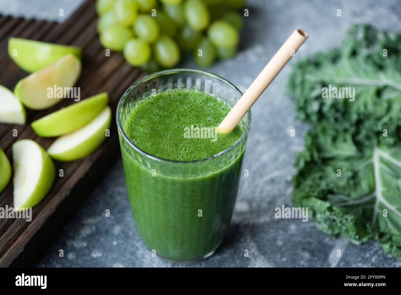 Frullato verde Detox in vetro con una paglia di bambù che beve, vista closeup Foto Stock