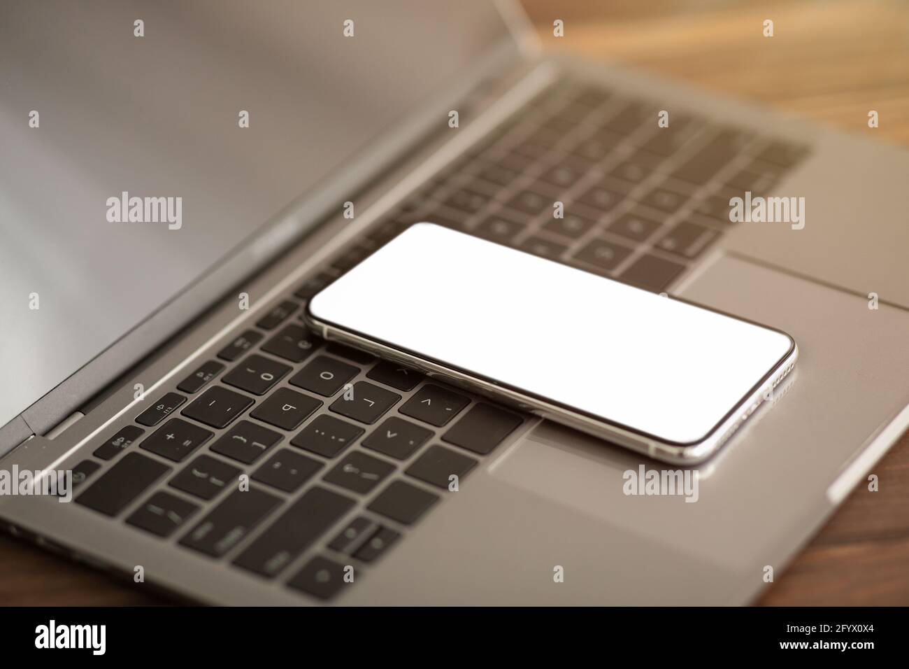 Smartphone moderno con schermo vuoto posizionato sulla tastiera del computer portatile, mockup per il design o la pubblicità sul cellulare Foto Stock