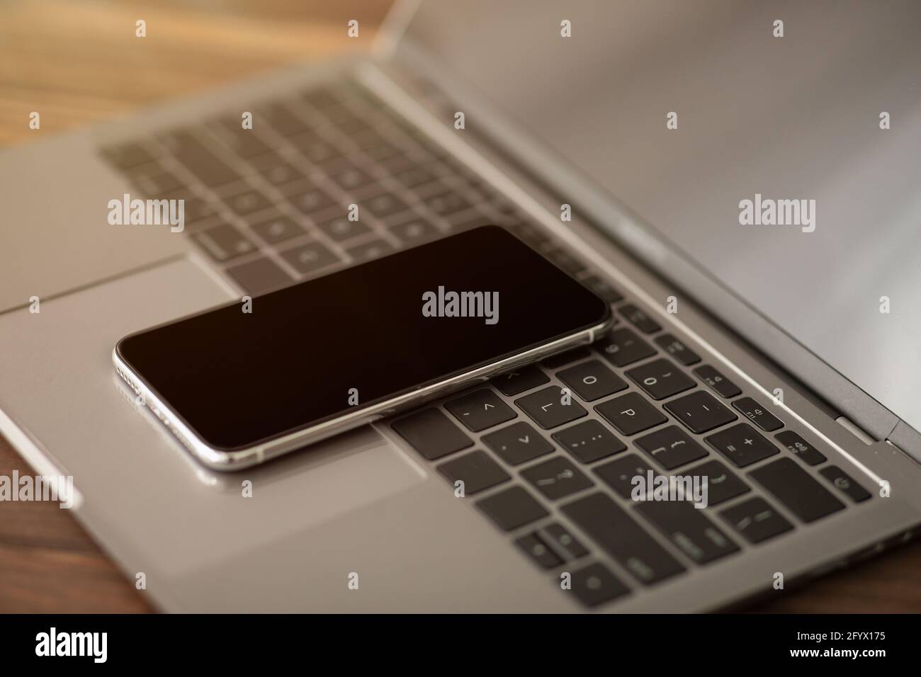 Smartphone con schermo nero posizionato sulla tastiera del computer portatile, primo piano. Tecnologie moderne nella vita di tutti i giorni Foto Stock