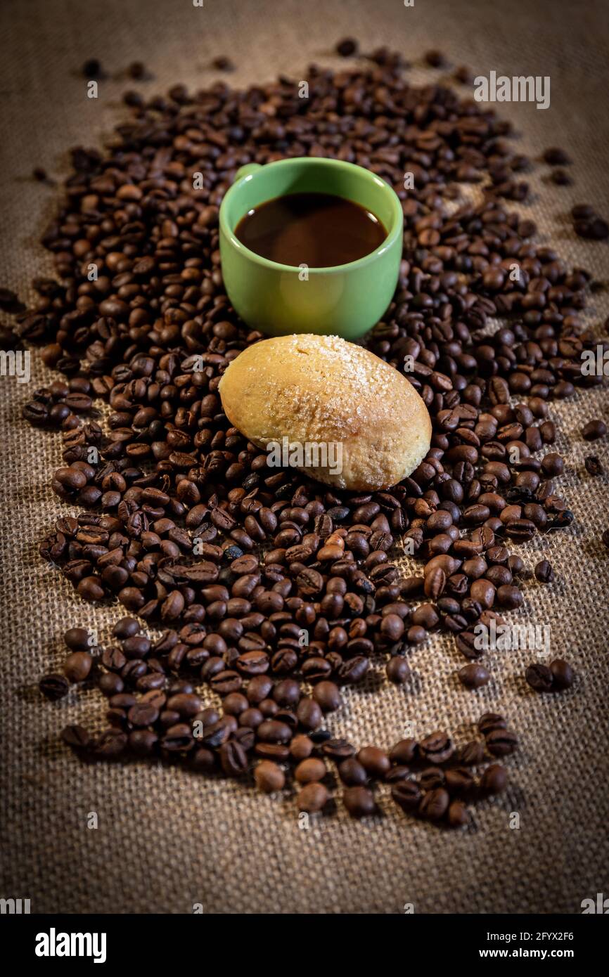 Concetto di colazione. Una tazza di caffè verde e un biscotto fatto in casa  circondato da chicchi di caffè. Un tessuto di iuta sullo sfondo Foto stock  - Alamy