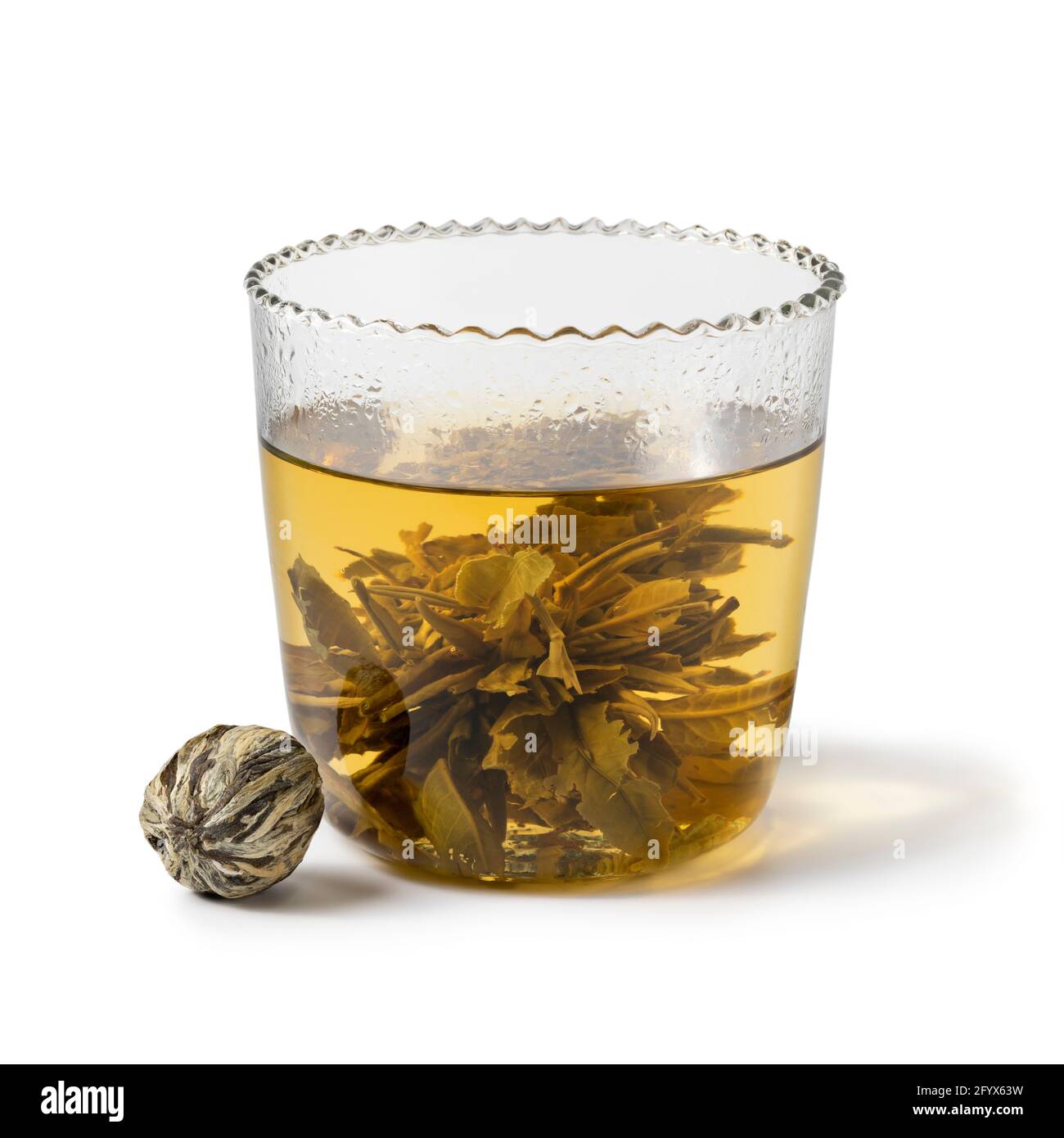 La perla cinese del tè essiccato cresce in una tazza di tè di vetro isolato su sfondo bianco Foto Stock