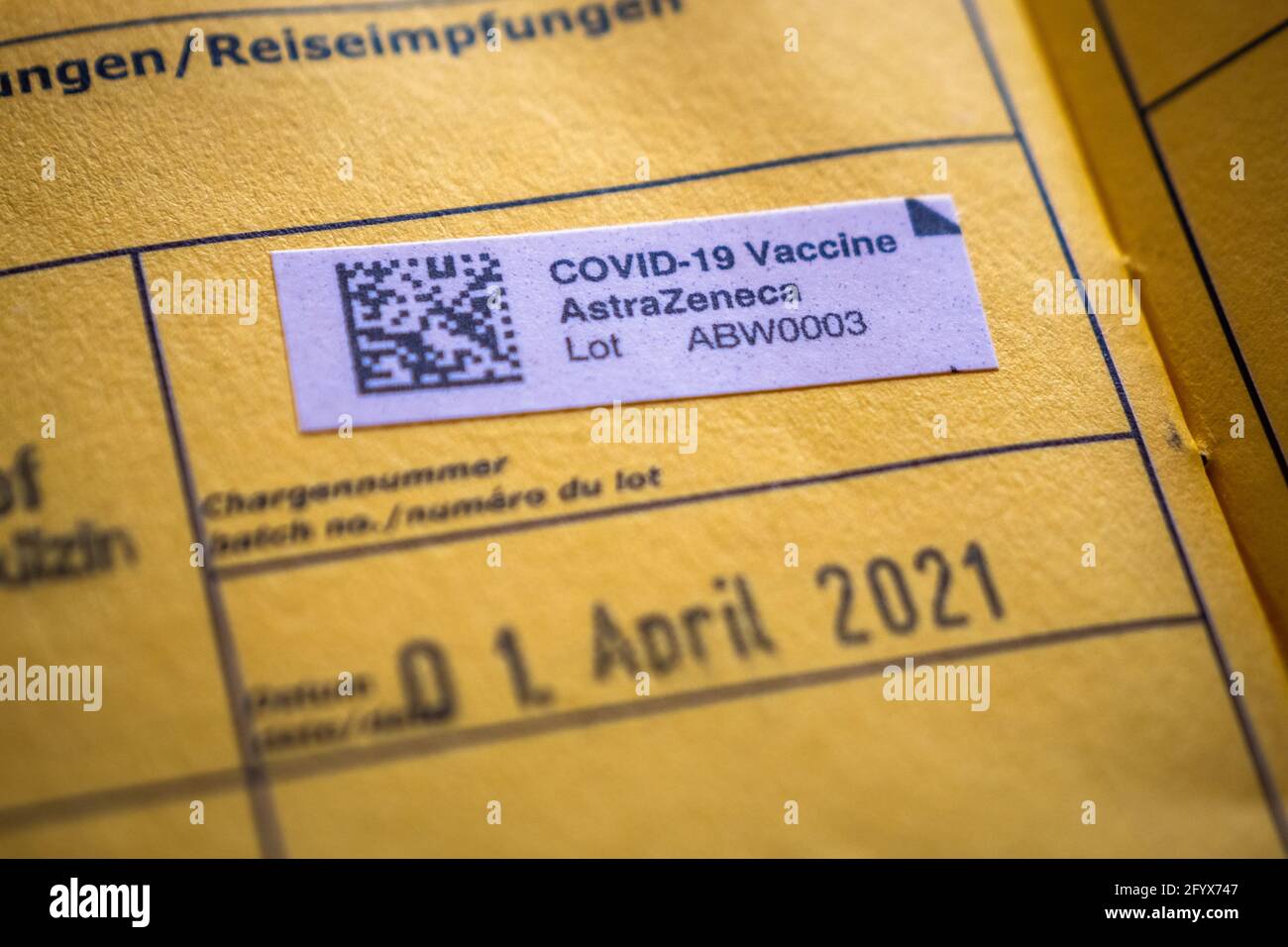 Amstetten, Austria - Maggio 30 2021: Adesivo vaccino AstraZeneca Covid-19 in un certificato di vaccinazione Internazionale giallo, un documento di certificazione Immuniza Foto Stock