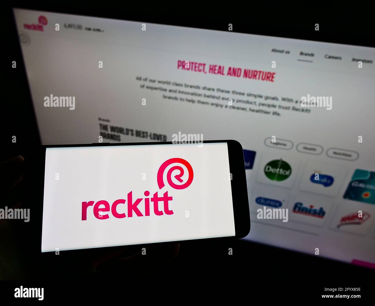 Persona che detiene il telefono cellulare con il logo della società di beni di consumo Reckitt Benckiser Group plc sullo schermo davanti alla pagina web. Mettere a fuoco il display del telefono. Foto Stock