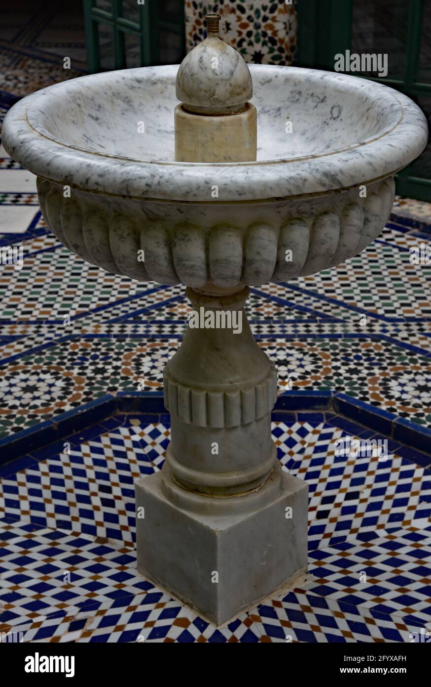 Fontana in marmo ornato, circondata da mosaici geometrici, in un cortile del Palazzo Bahia del XIX secolo, Marrakech, Marocco, Nord Africa. Foto Stock