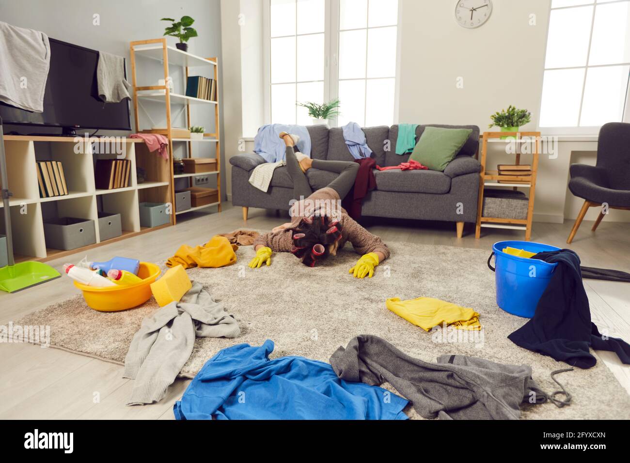 Sfinito giovane donna caduto sul pavimento durante la pulizia il suo soggiorno disordinato Foto Stock