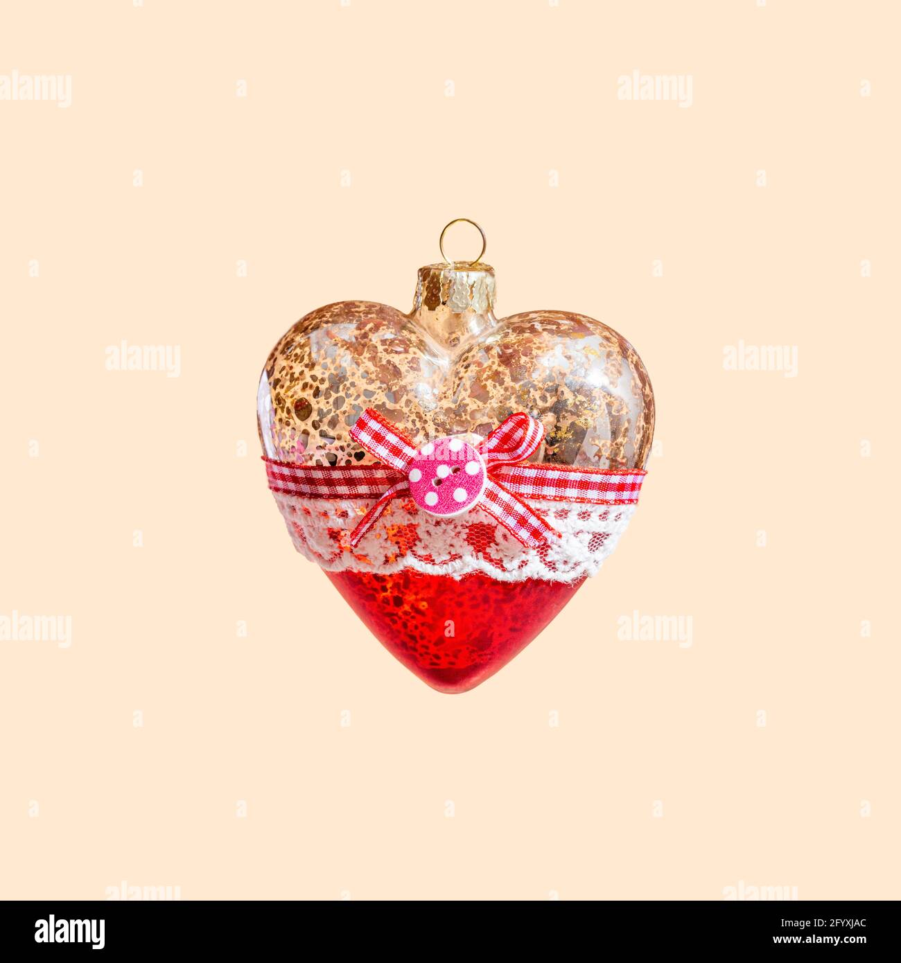 Il giocattolo dell'albero di Natale con il cuore in vetro svetta nell'aria su uno sfondo beige pastello. Concept anno nuovo Foto Stock