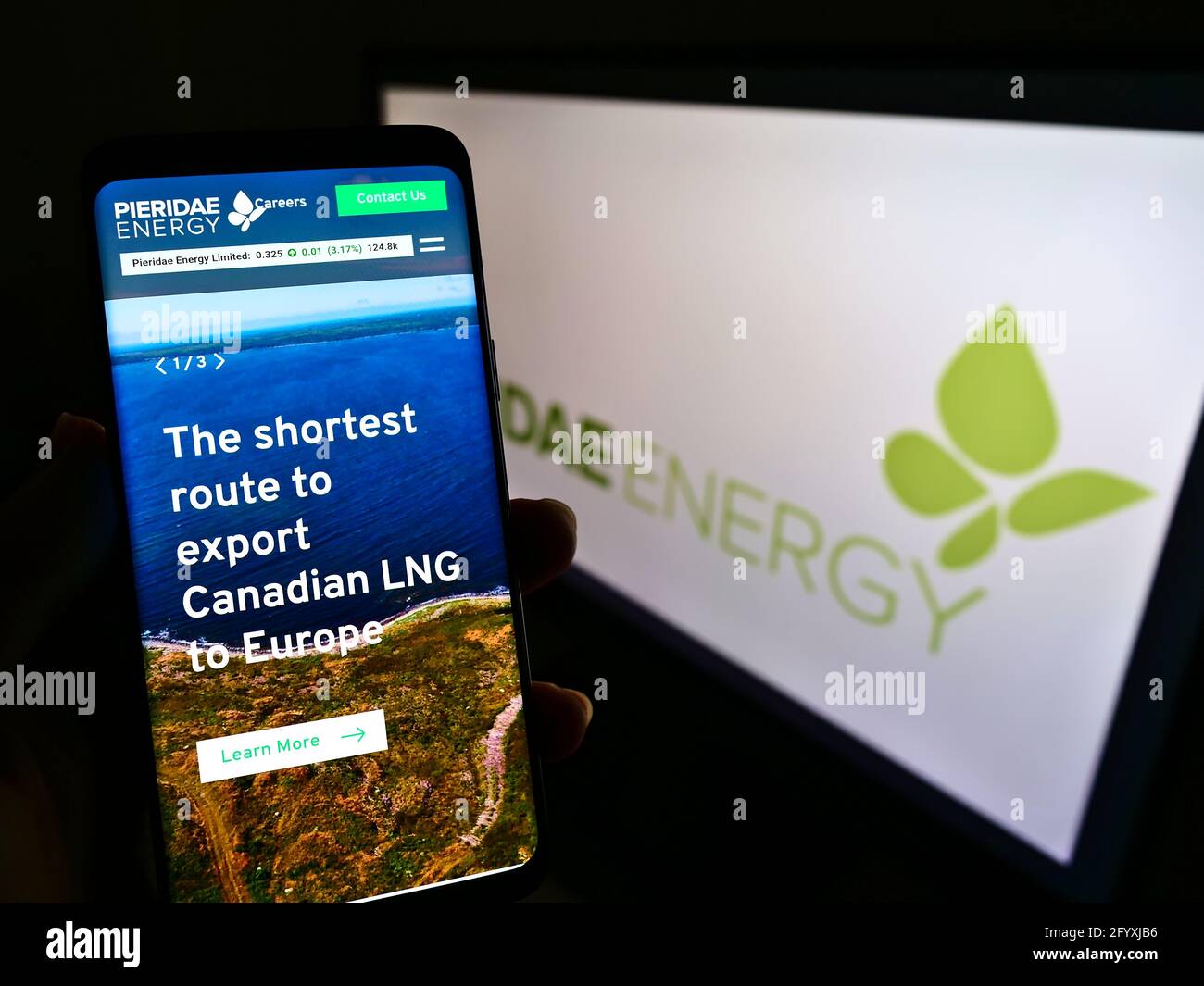 Persona titolare cellulare con pagina web della società canadese GNL Pieridae Energy Ltd. Sullo schermo davanti al logo. Mettere a fuoco il centro del display del telefono. Foto Stock