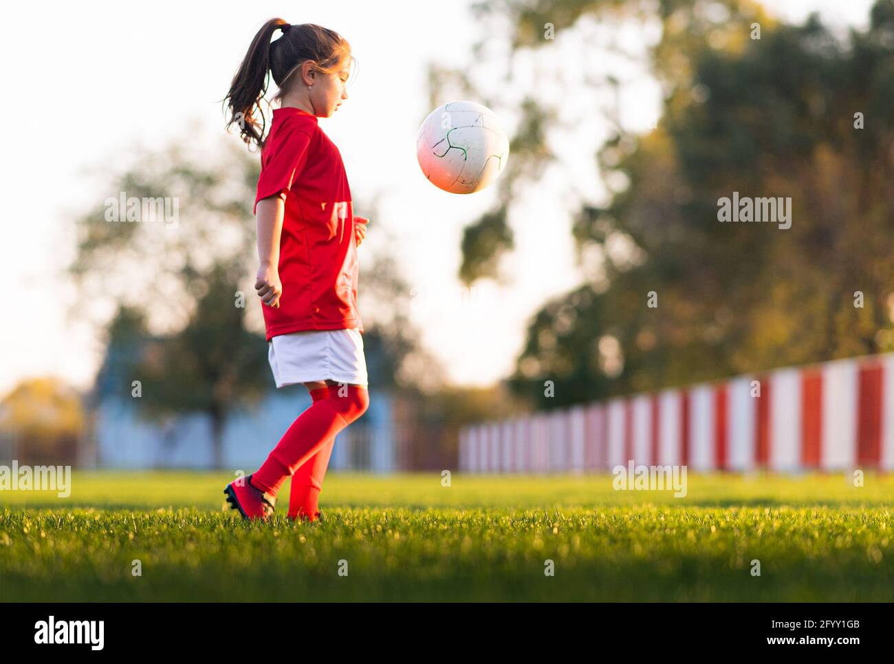 La ragazza calcia una palla di calcio su un campo di calcio Foto Stock