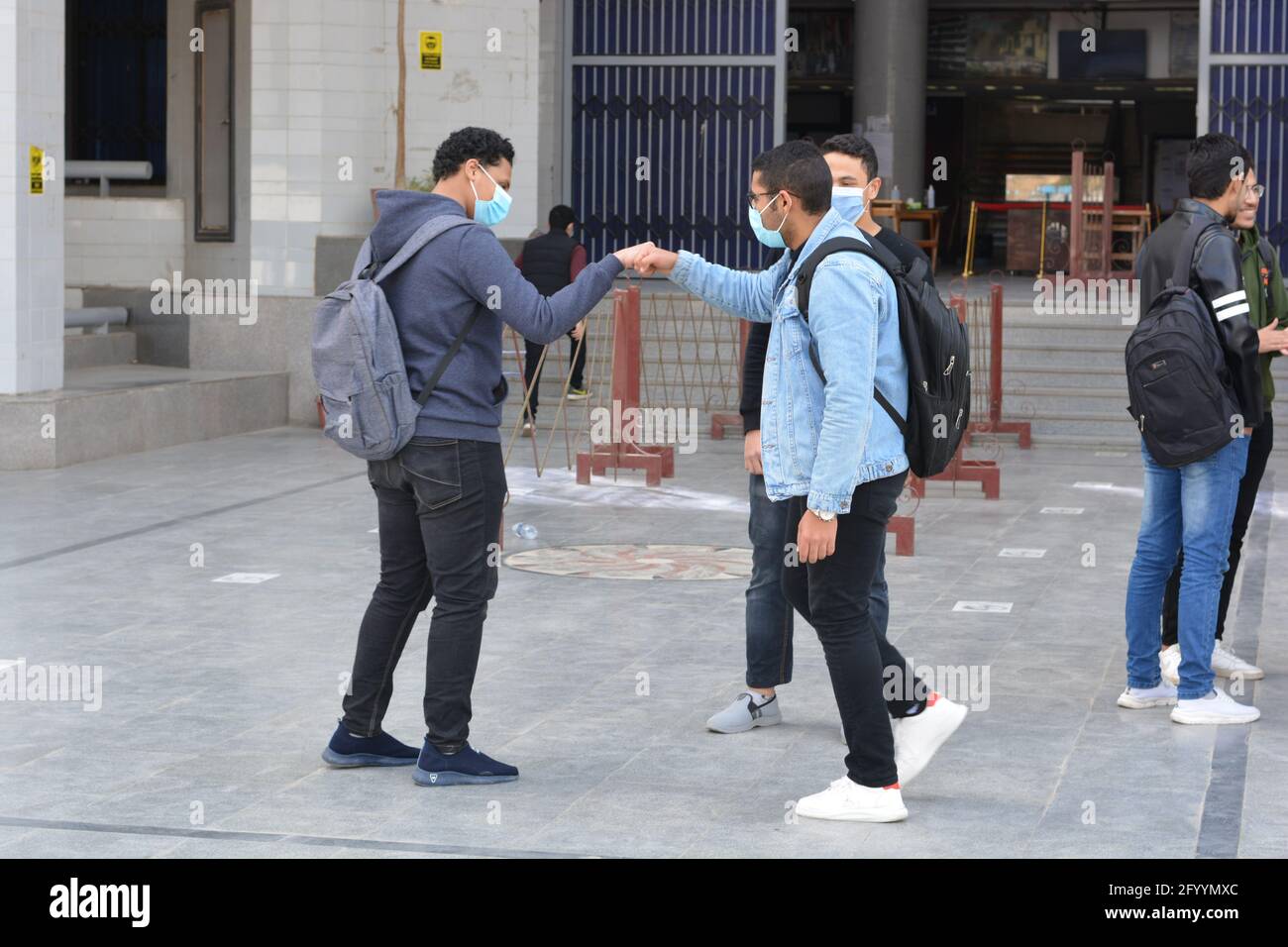 Gruppo di colleghi che indossano maschere protettive per il viso e pugno che urla durante una conversazione durante la pandemia di coronavirus, Fist bump durante Covid-19 Foto Stock