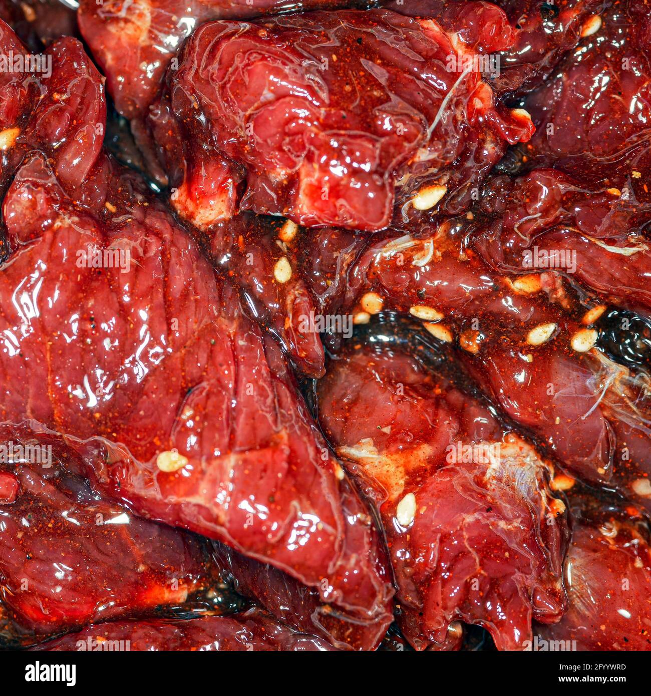 Fette di manzo marinate, luminose e succose, con spezie, olio e semi di sesamo Foto Stock