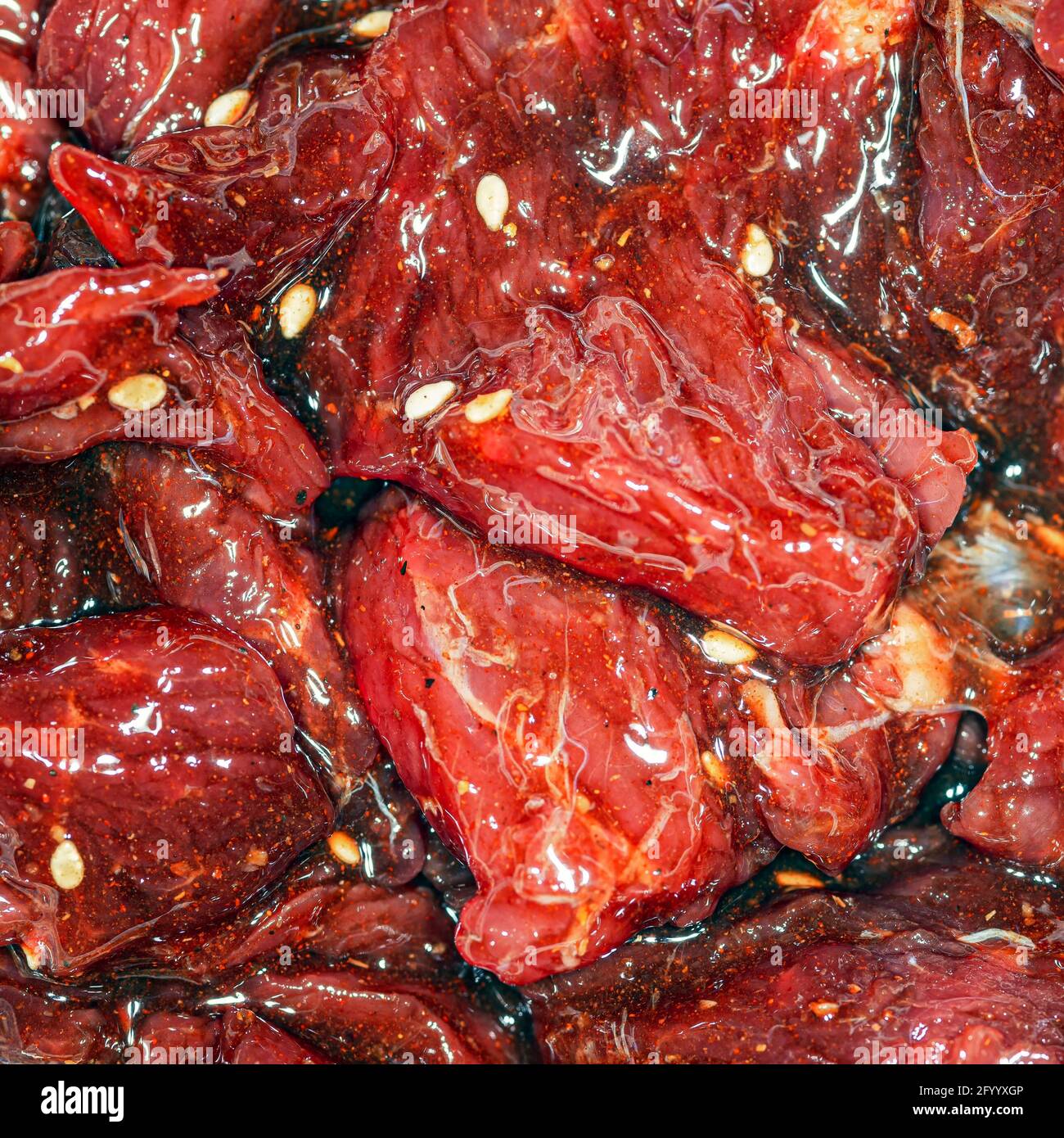 Fette di manzo marinate, luminose e succose, con spezie, olio e semi di sesamo Foto Stock