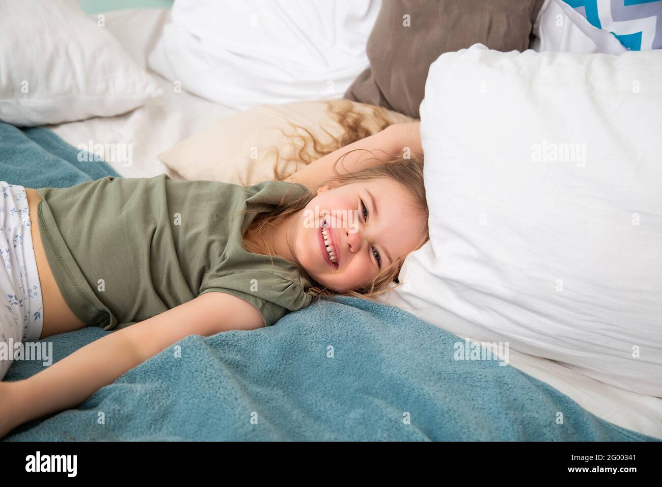 Ritratto di ragazza caucasica di età prescolare sdraiata sul letto e. sorridi guardando la fotocamera Foto Stock