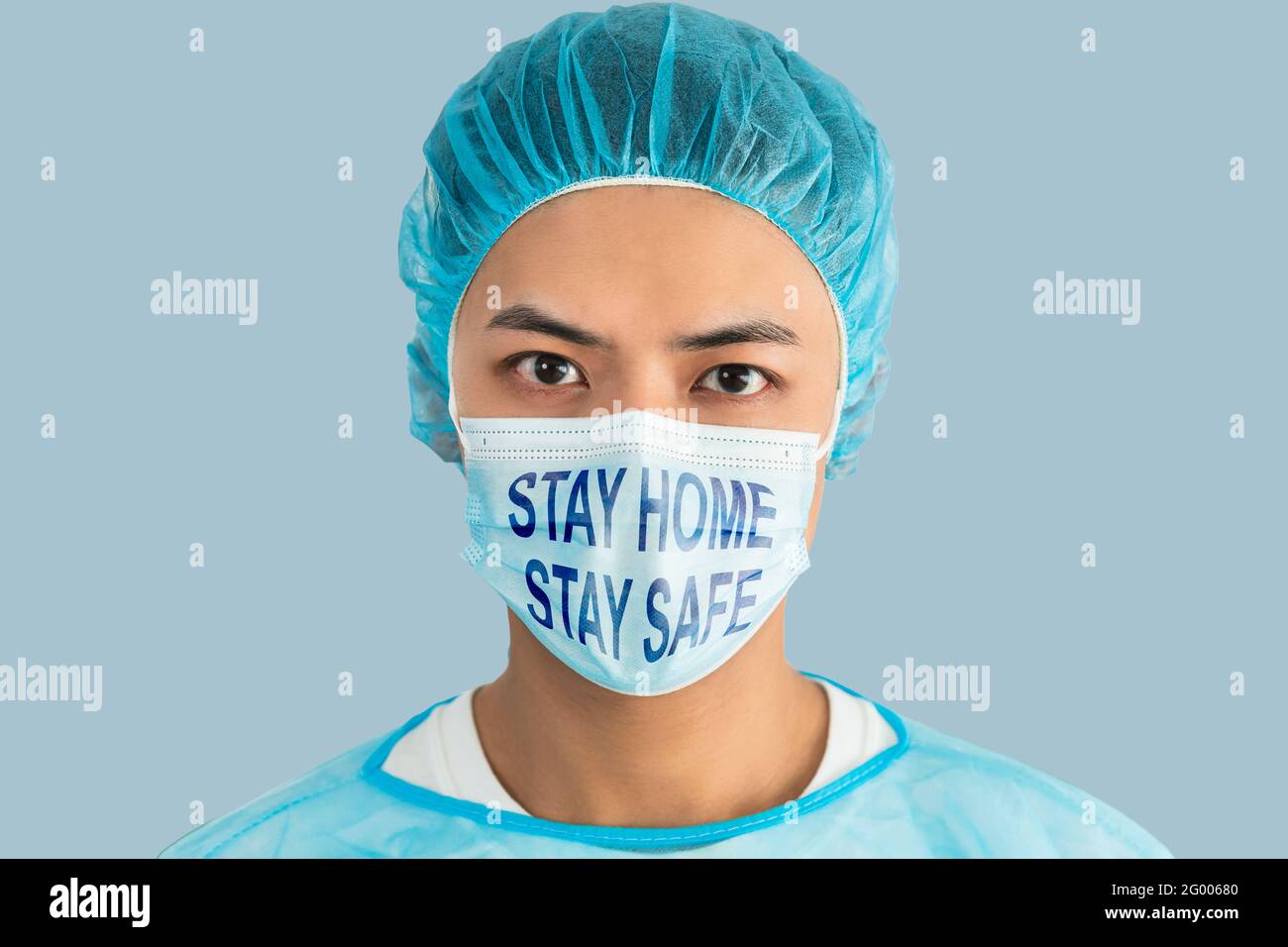 Medico indossare maschera viso, blu verde uniforme mostrando rimanere a casa rimanere sicuro concetti Foto Stock