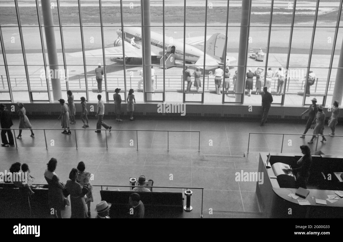 Visitatori che guardano gli aerei attraverso la finestra della sala d'attesa principale presso l'aeroporto municipale di Washington, DC, luglio 1941 Foto Stock