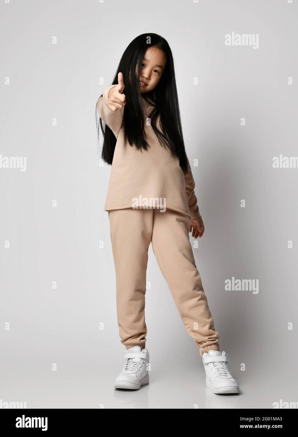 Happy asian Kid girl in verde abbigliamento sportivo casual pantaloni di  cotone, felpa con cappuccio, maglia e sneakers si alza come segno gesturing  Foto stock - Alamy