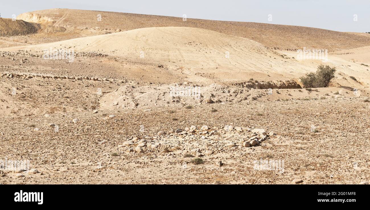 un piccolo cerchio di pietra antica e il sistema di canali d'acqua ad est Di Arad nel Negev in Israele con un moderno cava sullo sfondo a sinistra Foto Stock