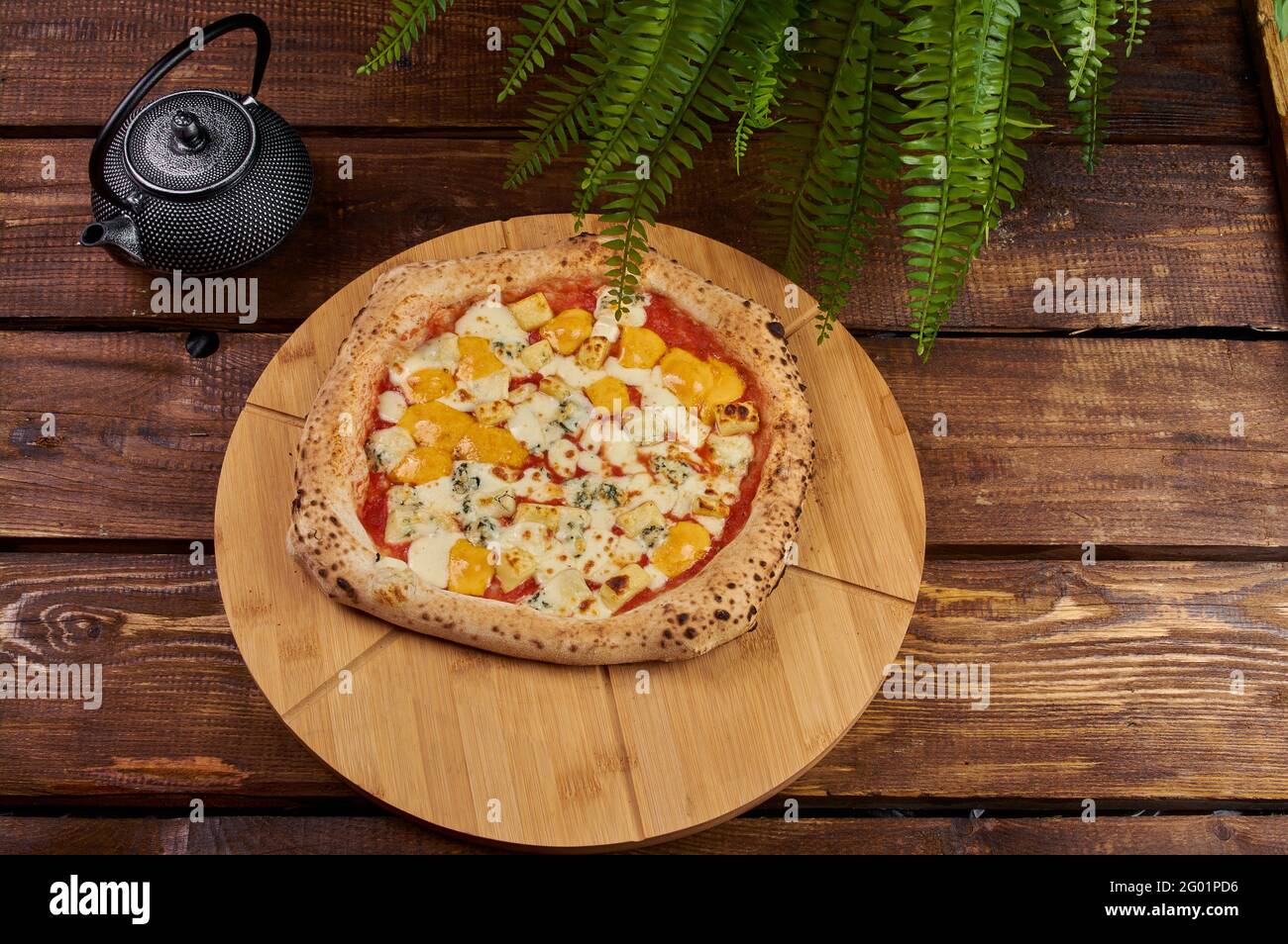 Pizza quattro formaggi su un supporto di legno Foto Stock