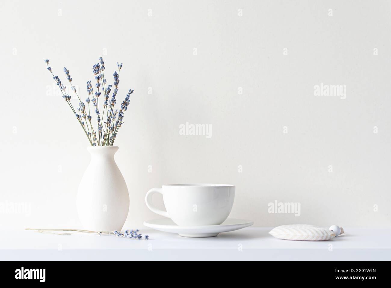 Vita still con composizione minima, bouquet di lavanda secca, tazza bianca in ceramica e bevanda calda tè o caffè, umore del mattino in tonalità beige Foto Stock