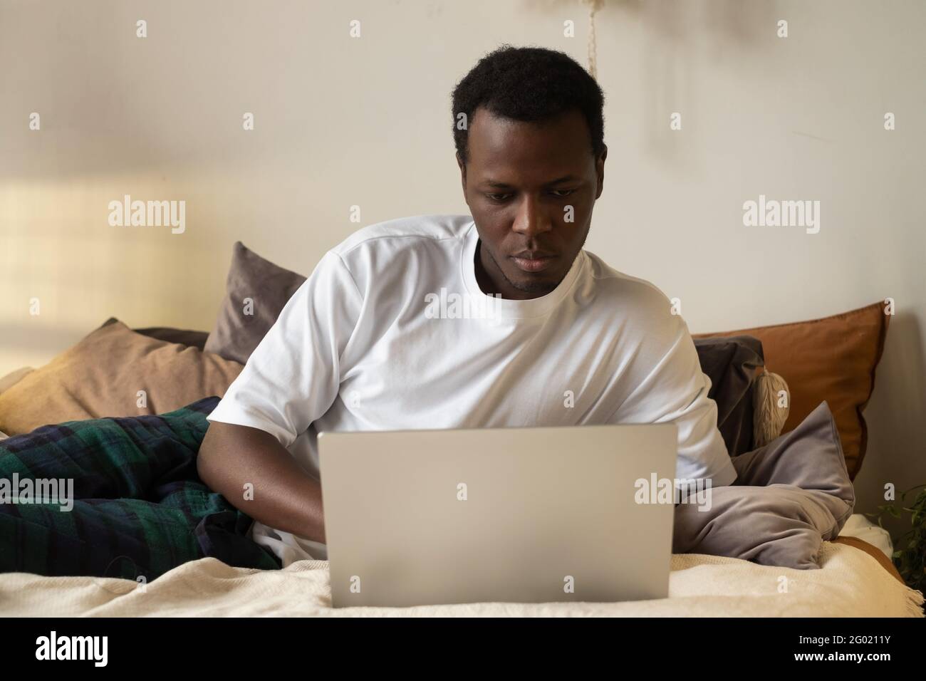 Uomo africano che naviga in internet nella sua stanza a casa Foto Stock