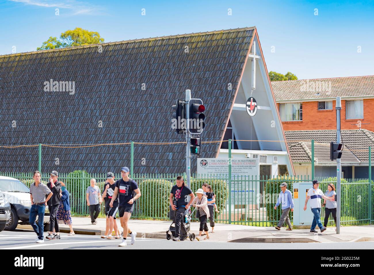 Persone che attraversano un incrocio vicino a una cornice, unendo la chiesa nel sobborgo occidentale di Sydney di Cabramatta in Australia Foto Stock