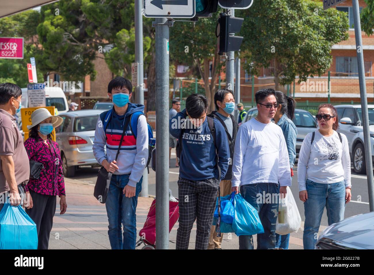 Gli australiani vietnamiti, alcuni indossando maschere, aspettano di attraversare una strada trafficata nel sobborgo di Sydney di Cabramatta New South Wales, Australia Foto Stock