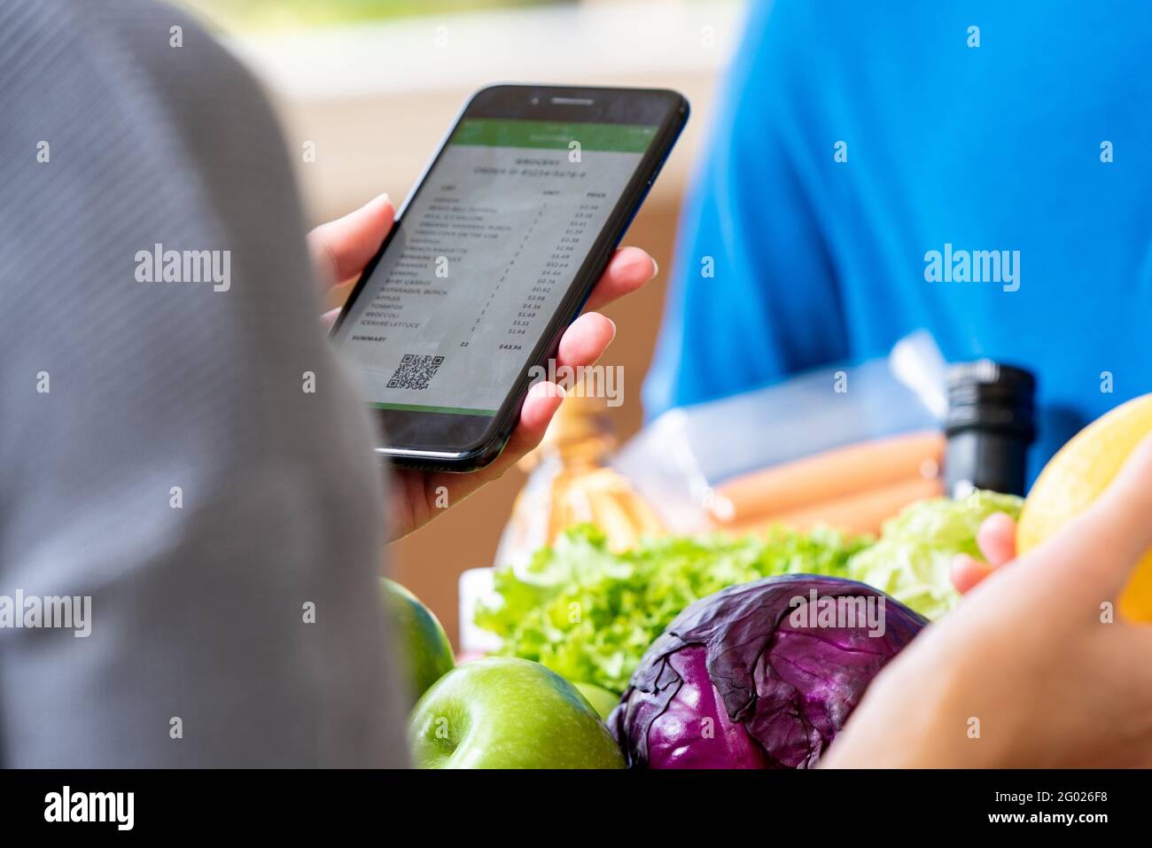 Cliente che controlla la drogheria che ha ordinato in linea e consegnato dal deliveryman a casa, concetto di servizio di consegna del cibo Foto Stock