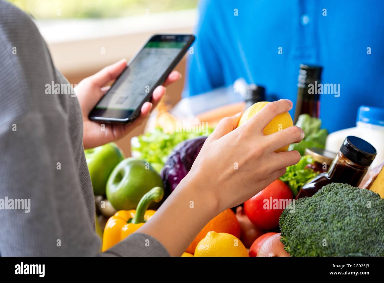 Cliente che controlla la drogheria che ha ordinato in linea e consegnato dal deliveryman a casa, concetto di servizio di consegna del cibo Foto Stock