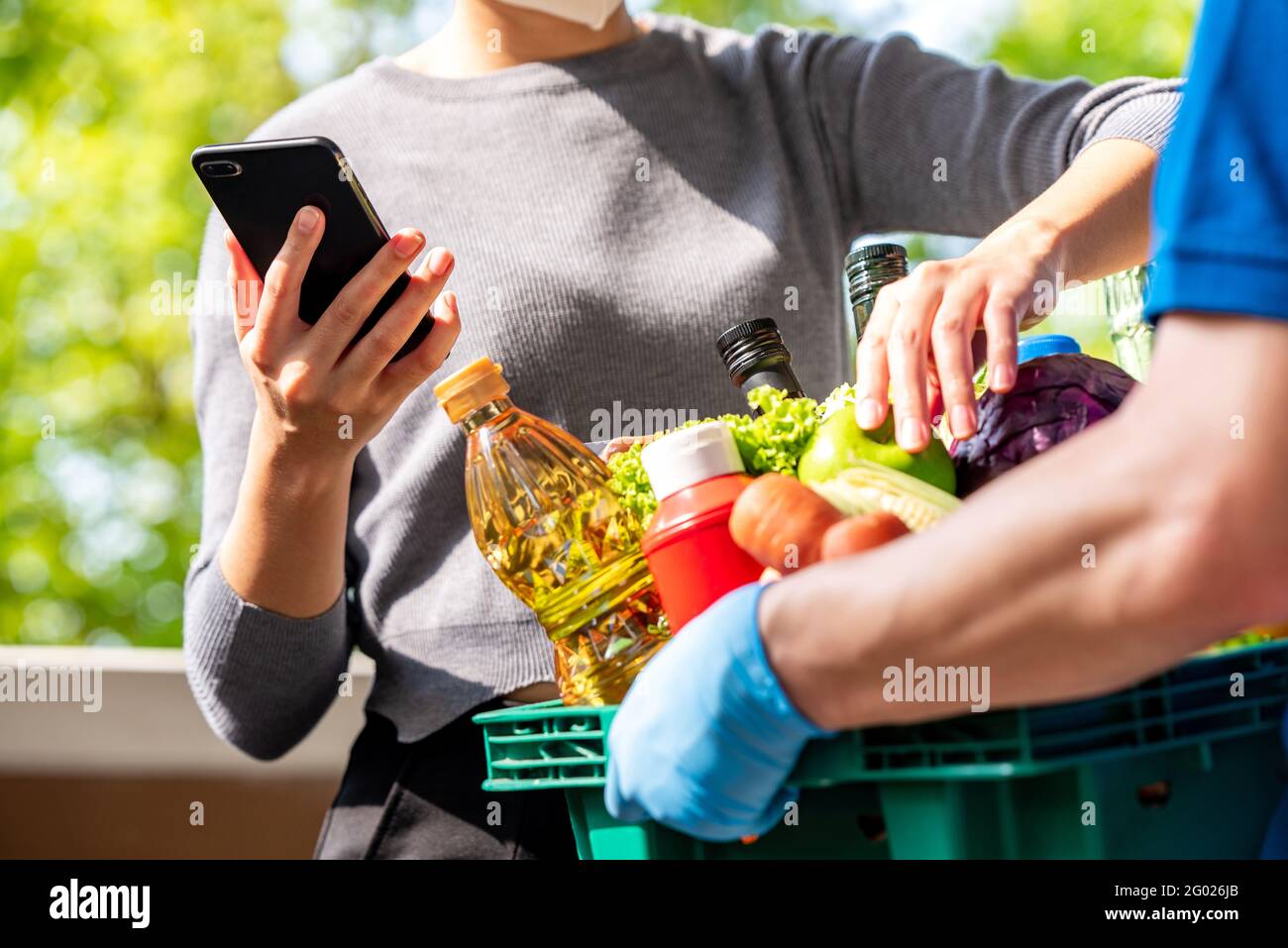 Donna cliente che controlla i generi alimentari che ha ordinato online e consegnato da deliveryman a casa, servizio di consegna di cibo nel momento del concetto pandemico Foto Stock