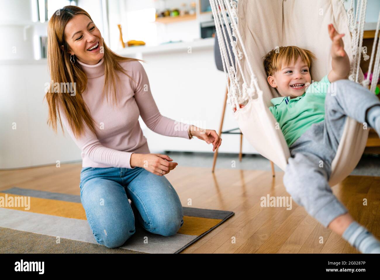 Gioioso ragazzo che si diverte, giocando con sua madre insieme a casa. Foto Stock