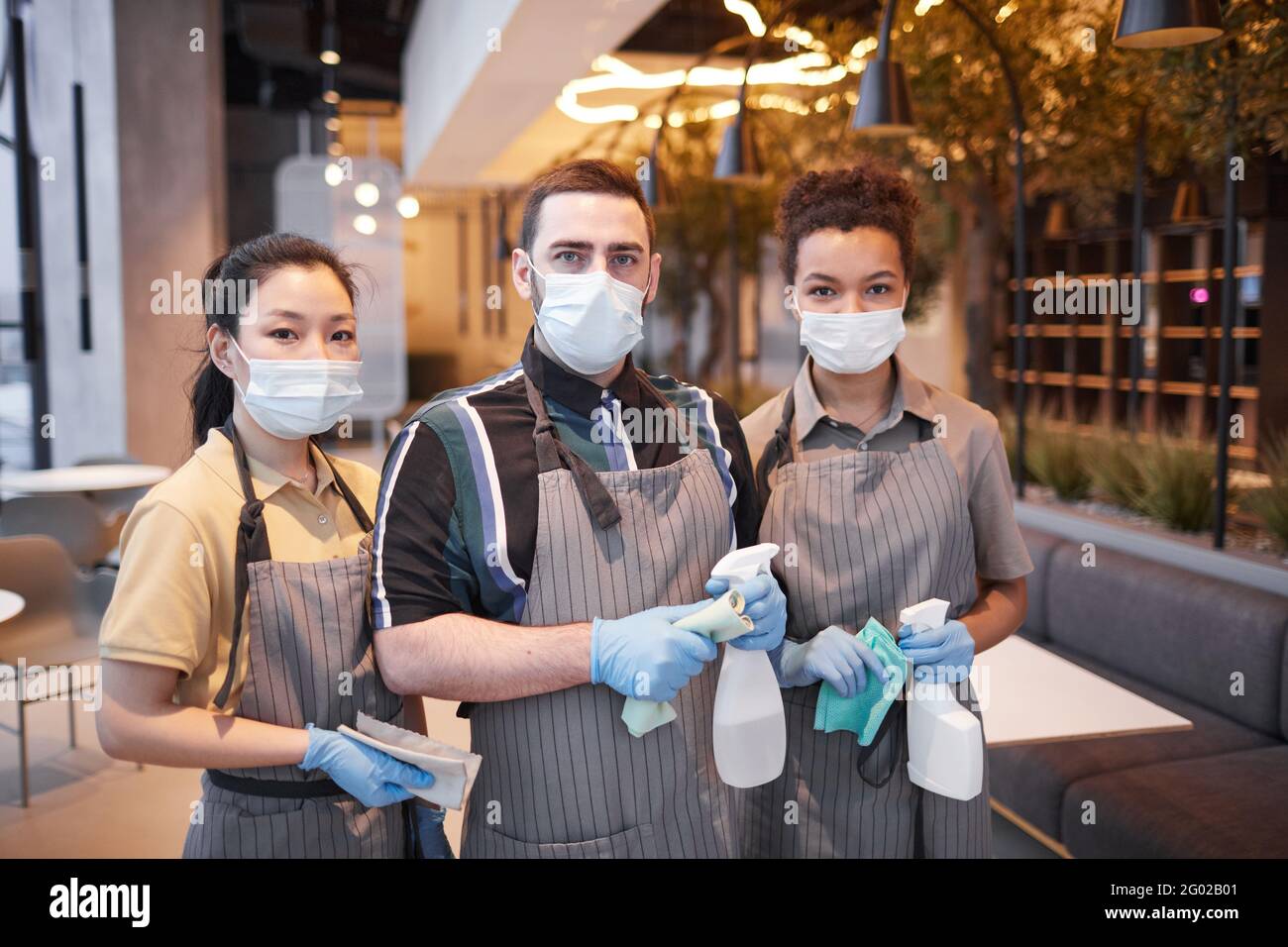 Vita in su ritratto di tre operai del caffè che indossa le maschere e guardando la macchina fotografica, concetto di sicurezza covid, spazio di copia Foto Stock