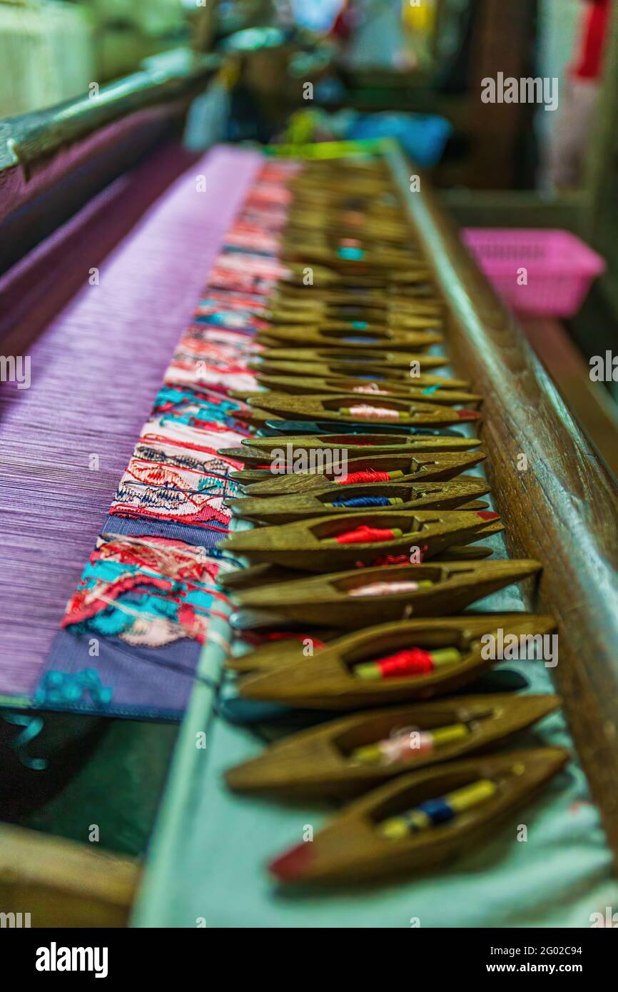 Tradizionale tecnica di tessitura artigianale per produrre un prodotto di seta a motivo colorato Foto Stock