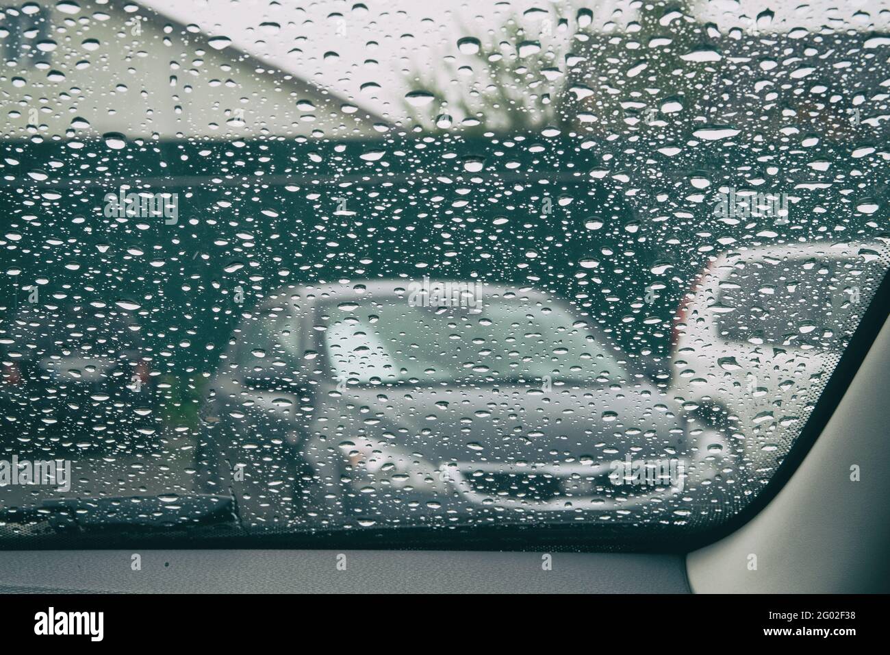 Gocce di pioggia sul bicchiere è malinconico. Cade sul finestrino dell'auto. Dentro l'auto quando piove. Foto Stock