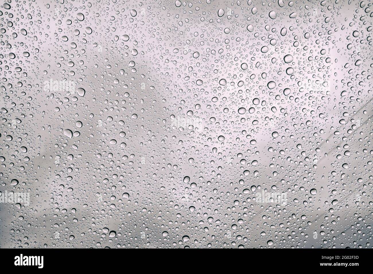 Gocce di pioggia sul bicchiere è malinconico. Cade sul finestrino dell'auto. Giornata invernale in città. Foto Stock
