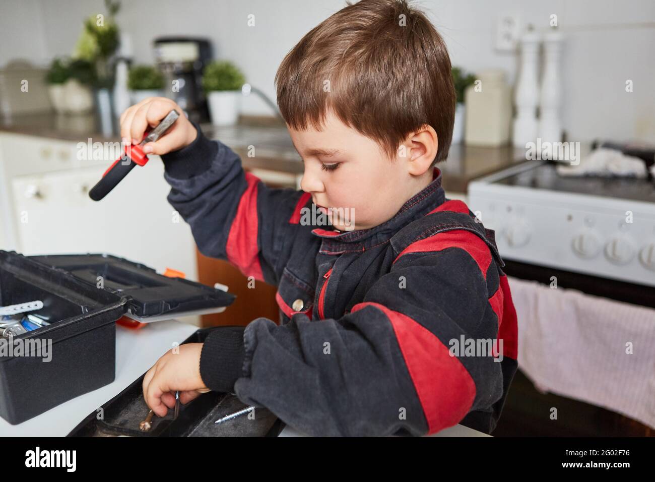 Bambino gioca artigiano o idraulico e tidie sulla cassetta degli attrezzi Foto Stock