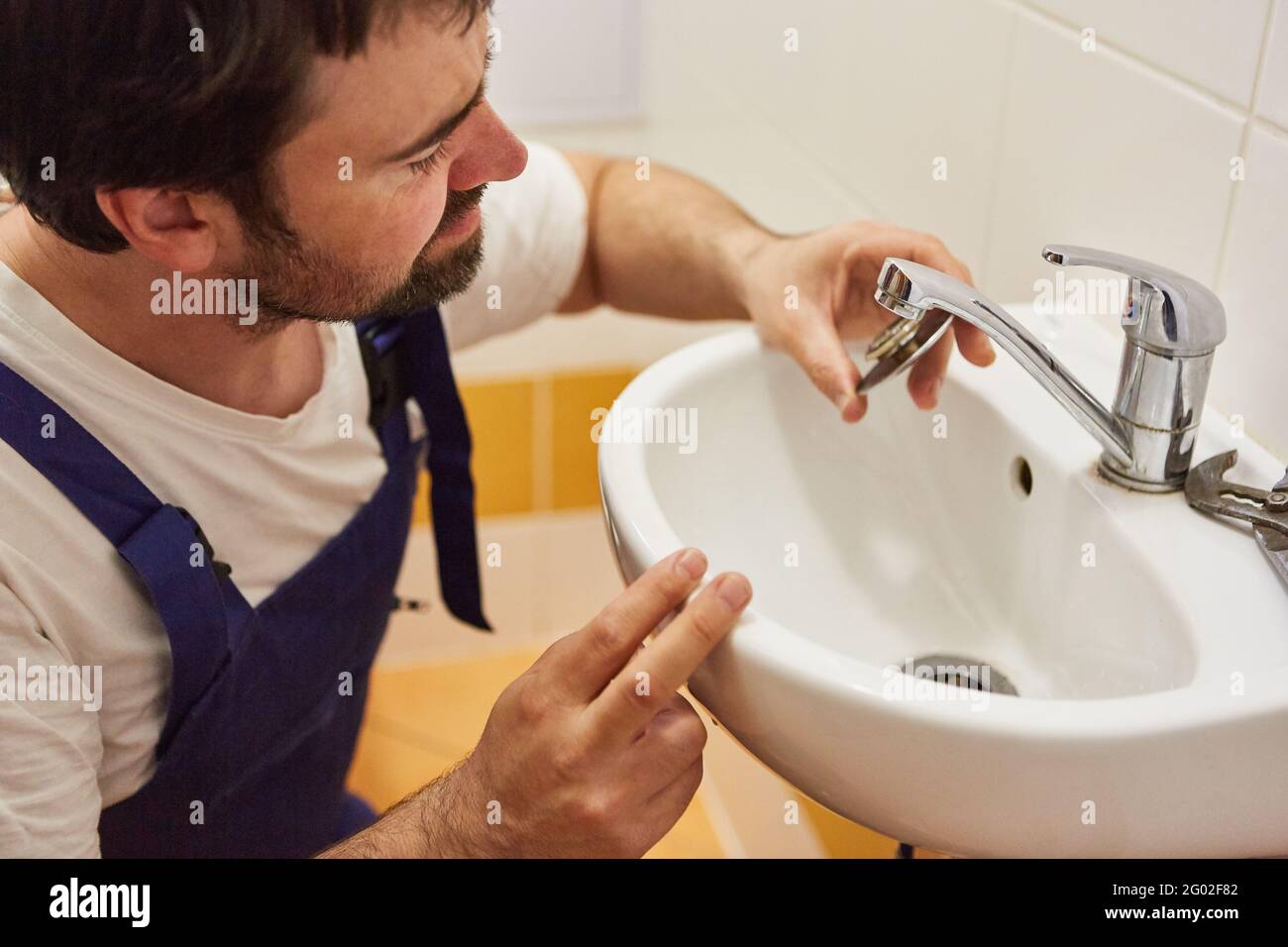 Fai-te-yourselfers o idraulico che ripara il rubinetto sul lavabo dentro il  bagno Foto stock - Alamy