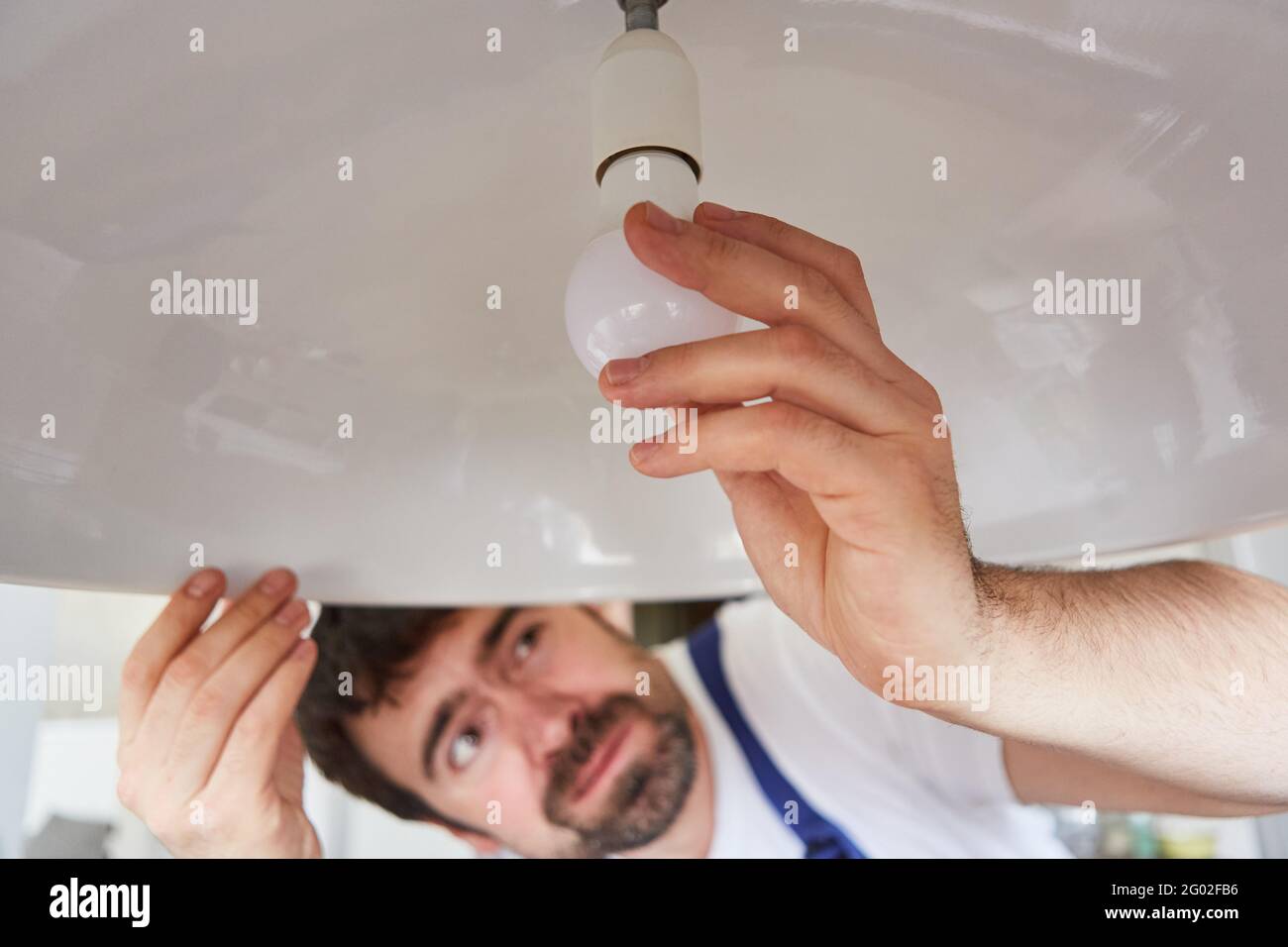 Fai-da-te-selfs o artigiani scambia le lampadine difettose sulla lampada da soffitto Foto Stock