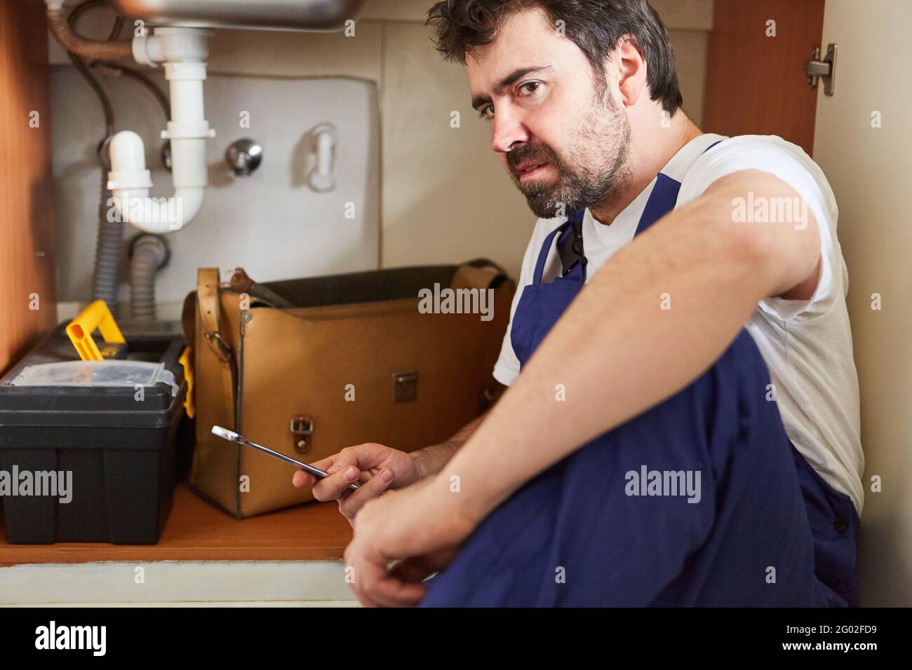 Uomo che lavora come handyman o idraulico che installa o ripara un lavandino Foto Stock