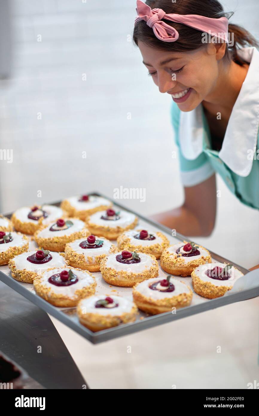 Il proprietario di piccola impresa grazioso è appassionato circa il suo prodotto/ciambelle Foto Stock