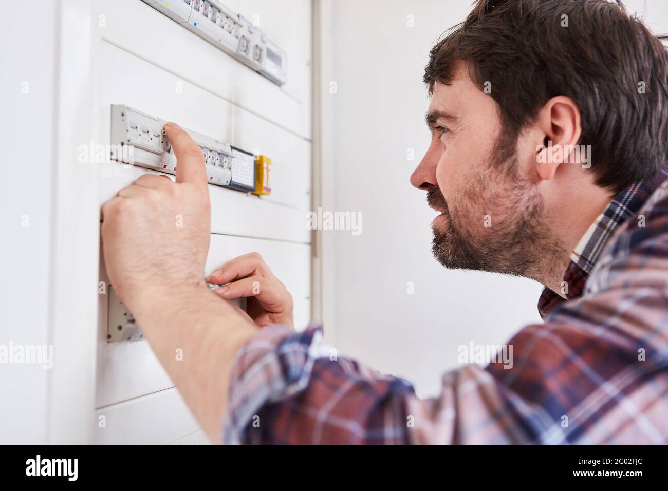 L'elettricista controlla il fusibile nella scatola di distribuzione di un appartamento Foto Stock